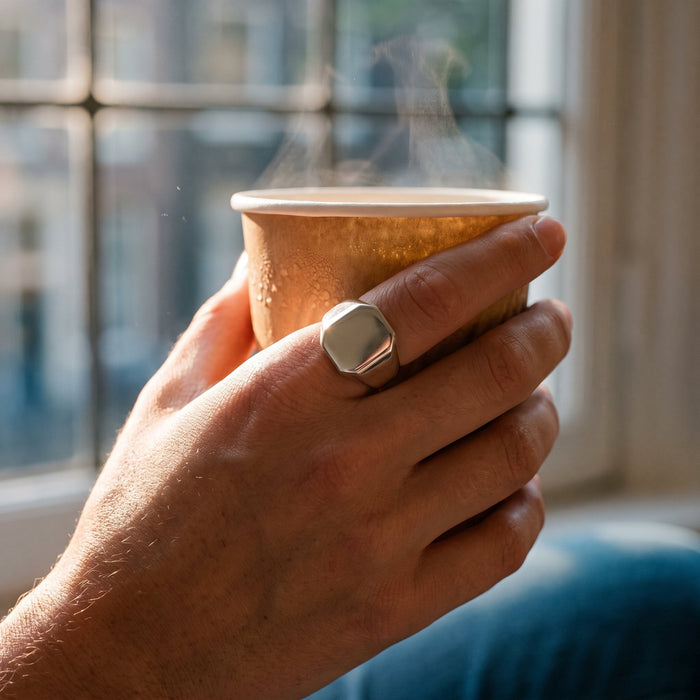 Dominius zegelring gedragen, hand om warme koffiebeker in ochtendlicht