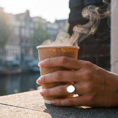 Monarque zegelring gedragen, hand om warme koffiebeker in ochtendlicht